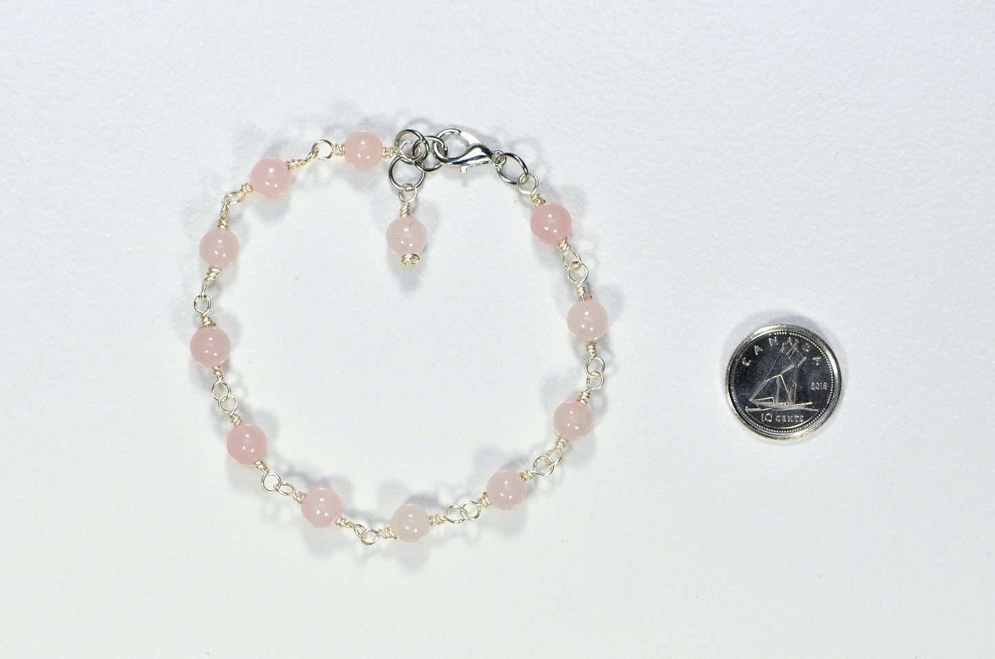 6mm Rose Quartz Link Bracelet beside a dime.