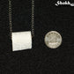 Miniature Toilet Paper Roll Necklace beside a dime.