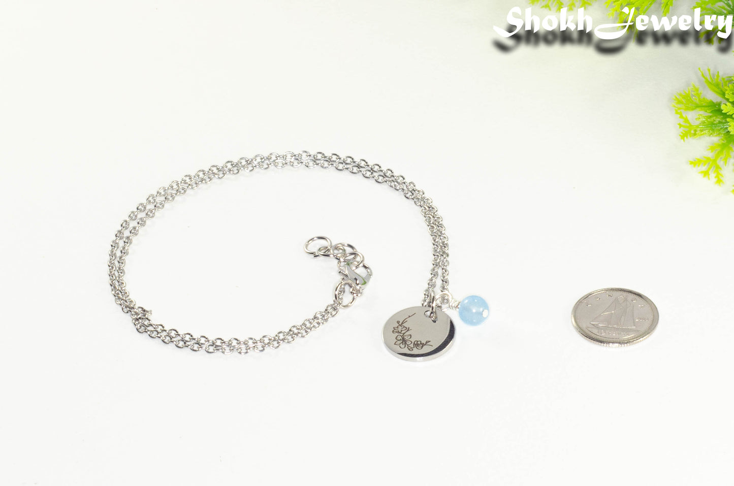 March Birth Flower Necklace with Aquamarine Birthstone Pendant beside a dime.