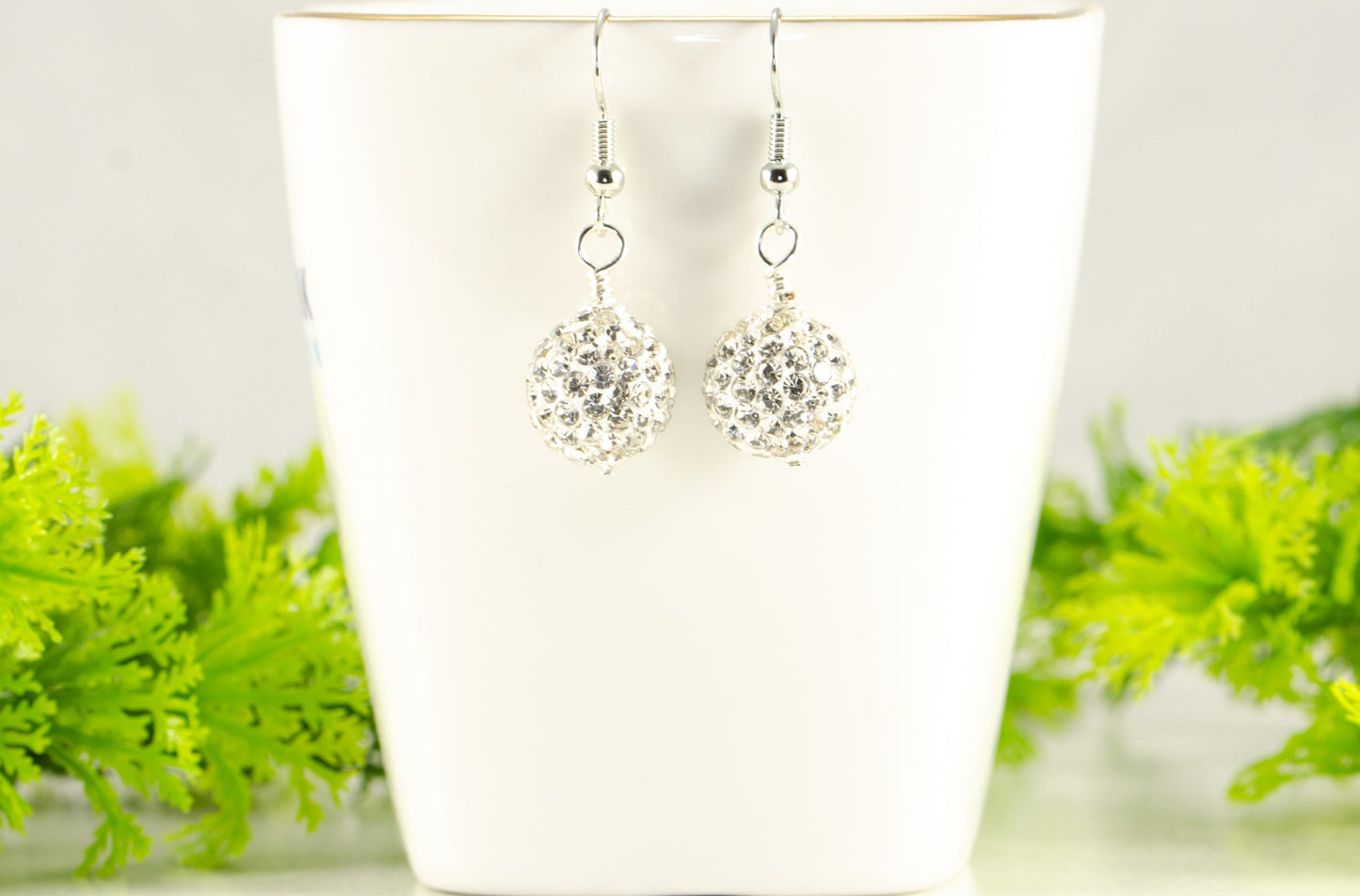 12mm Rhinestone Disco Ball Earrings displayed on a tea cup.