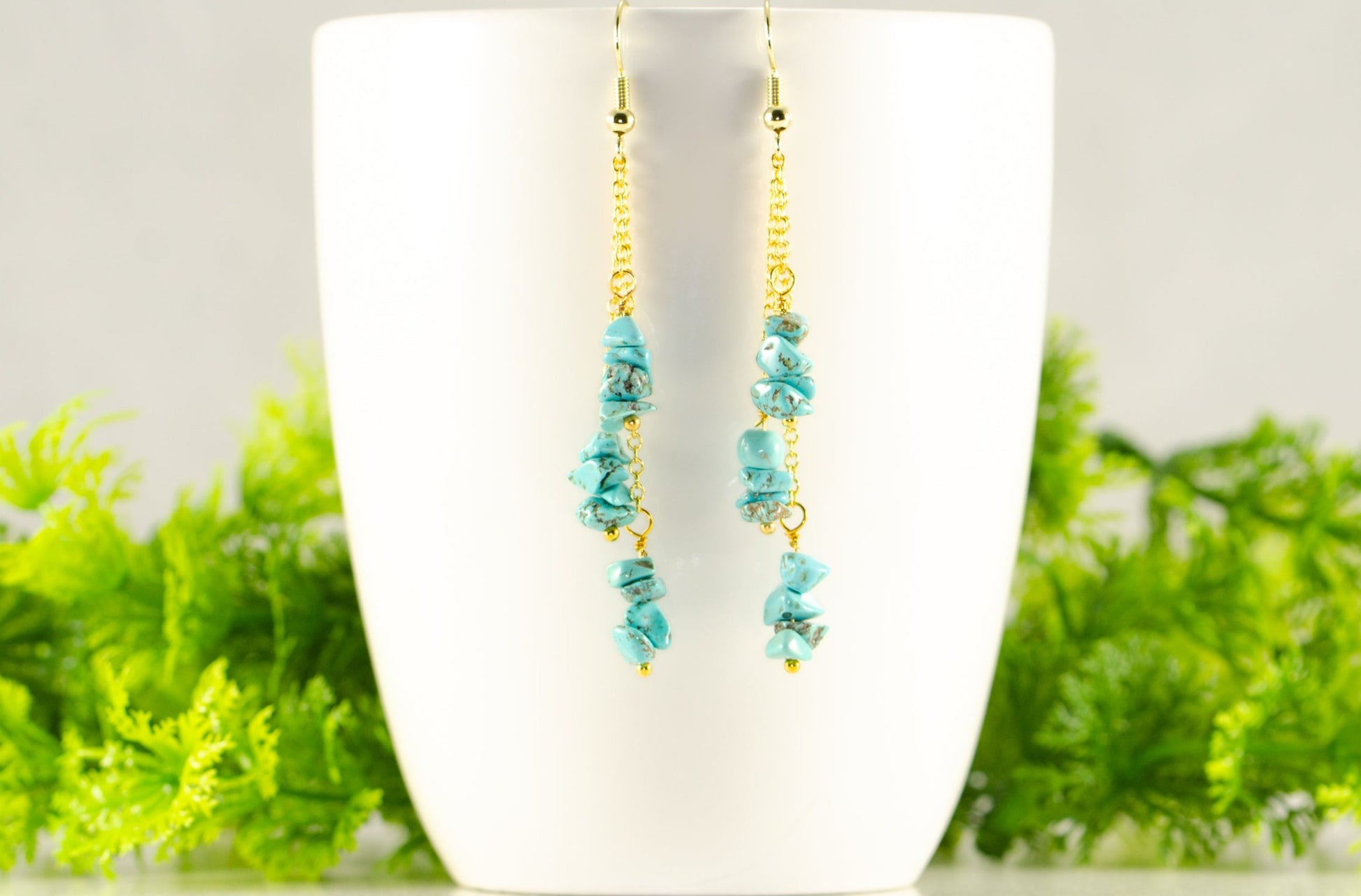 Long Gold Plated Chain and Turquoise Crystal Chip Earrings displayed on a coffee mug.