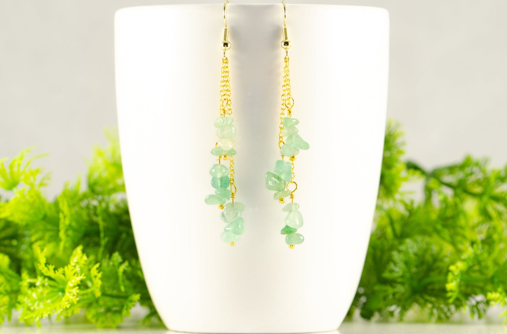 Long Gold Plated Chain and Green Aventurine Chip Earrings displayed on a coffee mug.