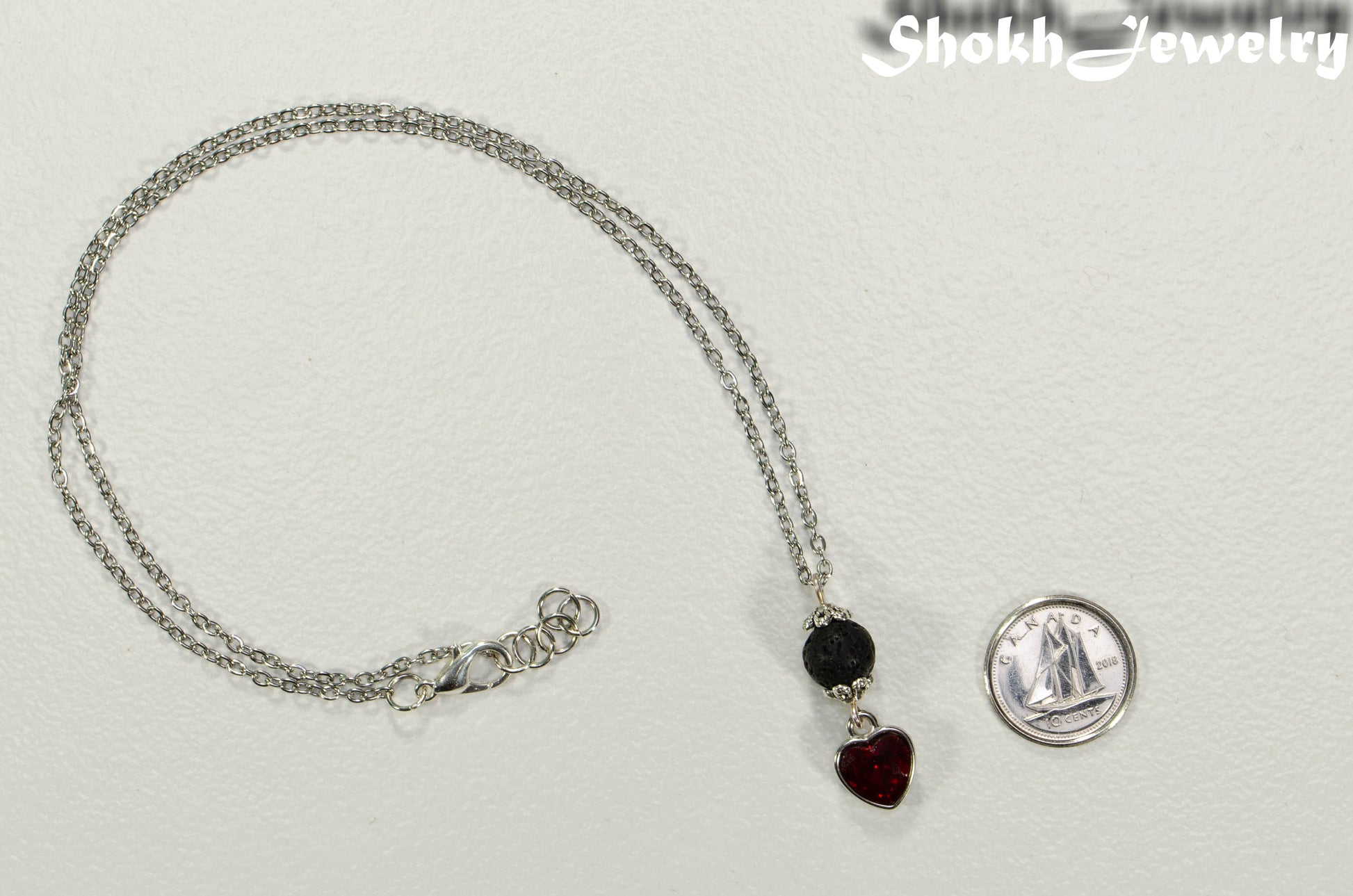 Lava Rock and Heart Shaped January Birthstone Choker Necklace beside a dime.