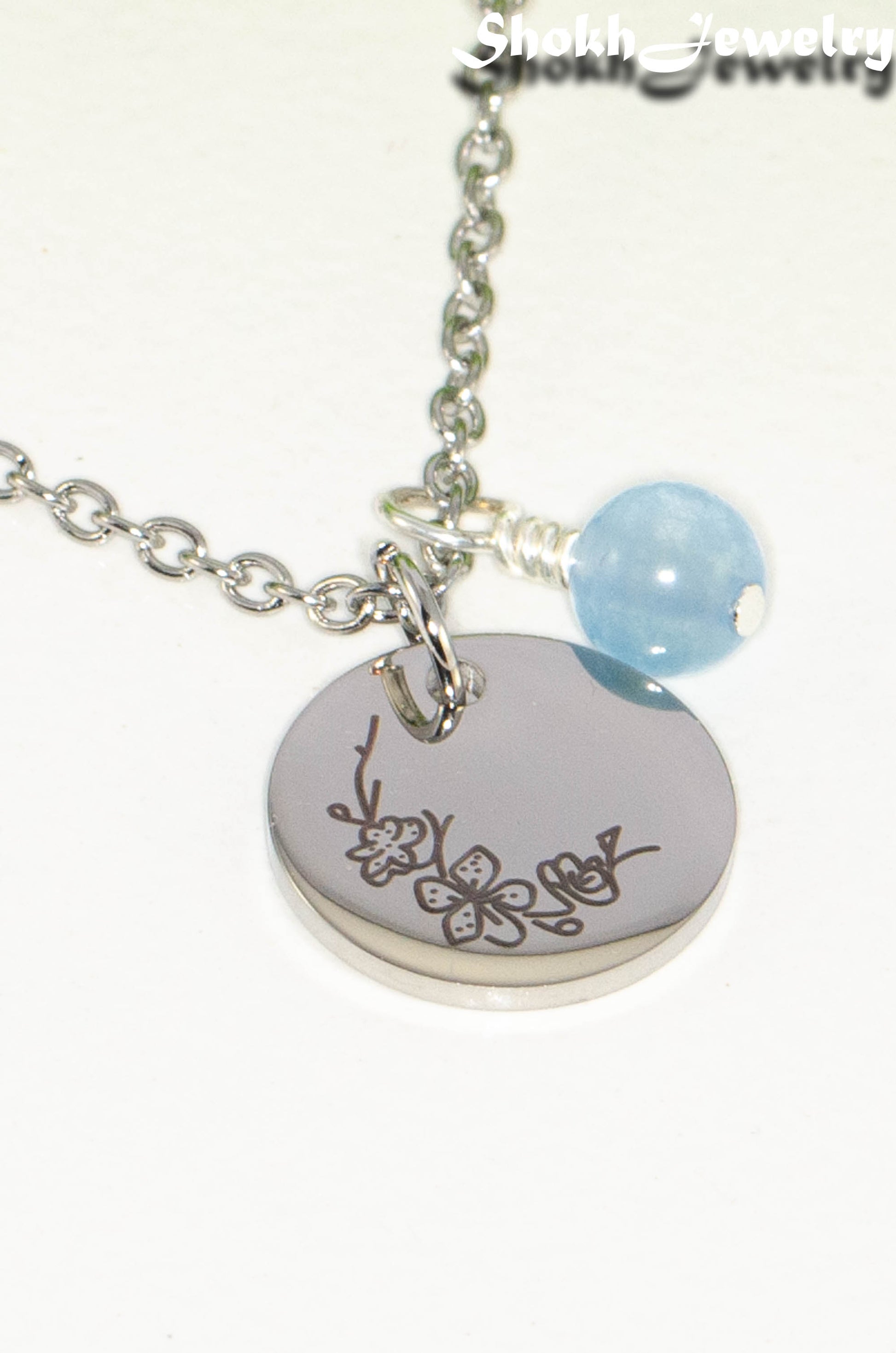 Close up of March Birth Flower Necklace with Aquamarine Birthstone Pendant.