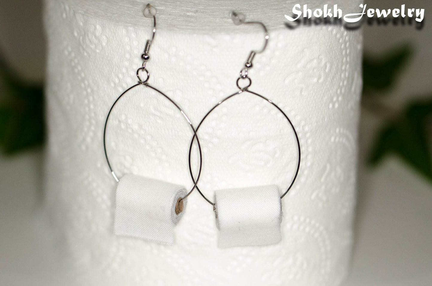 Miniature Toilet Paper Roll Earrings displayed on a toilet paper roll.