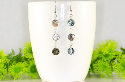 Elegant Long Natural Abalone Shell Earrings displayed on a coffee mug.