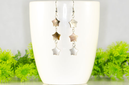Long Natural Seashell Star Earrings displayed on a coffee mug.