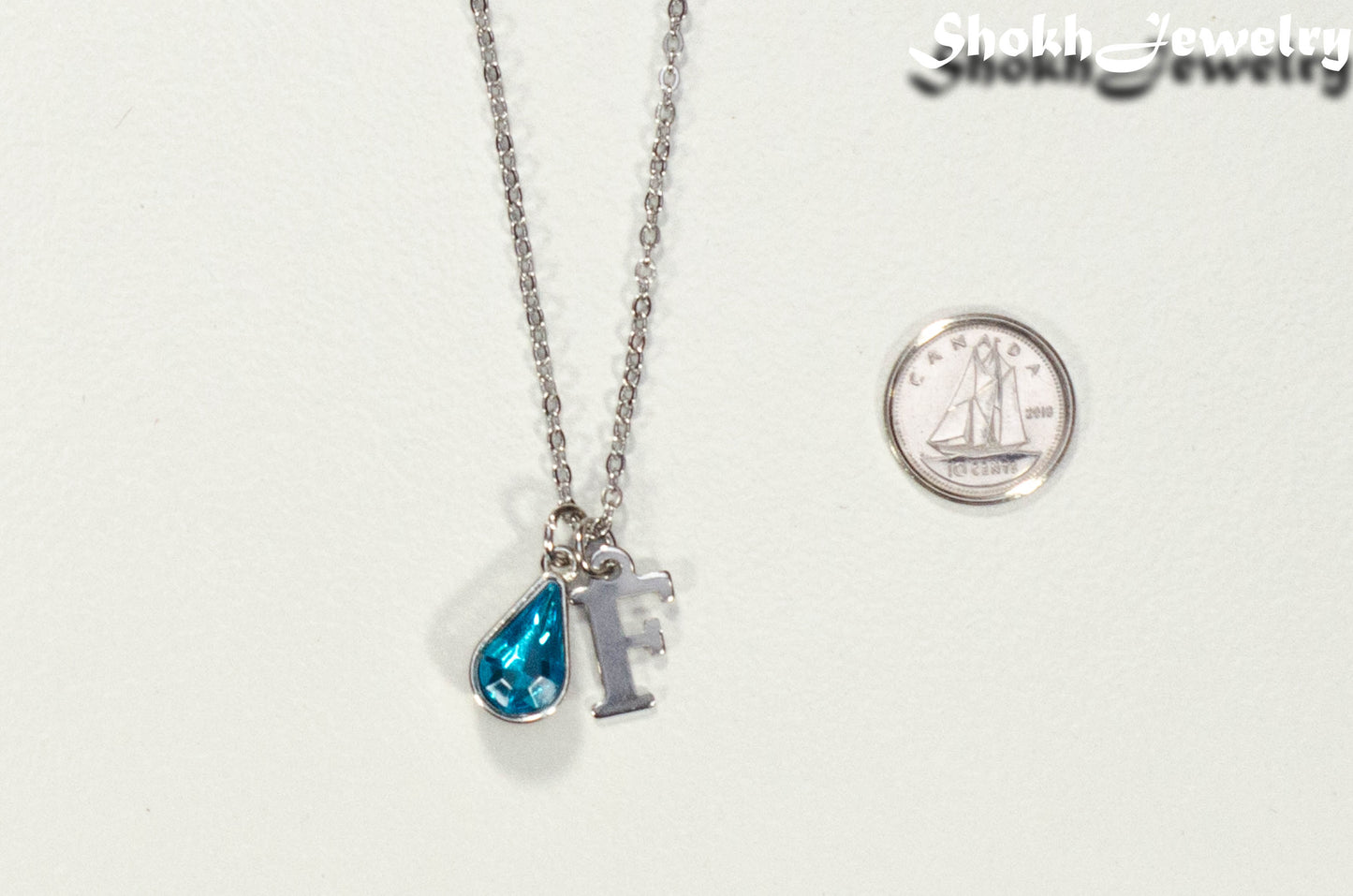 Personalized March Birthstone pendant beside a dime