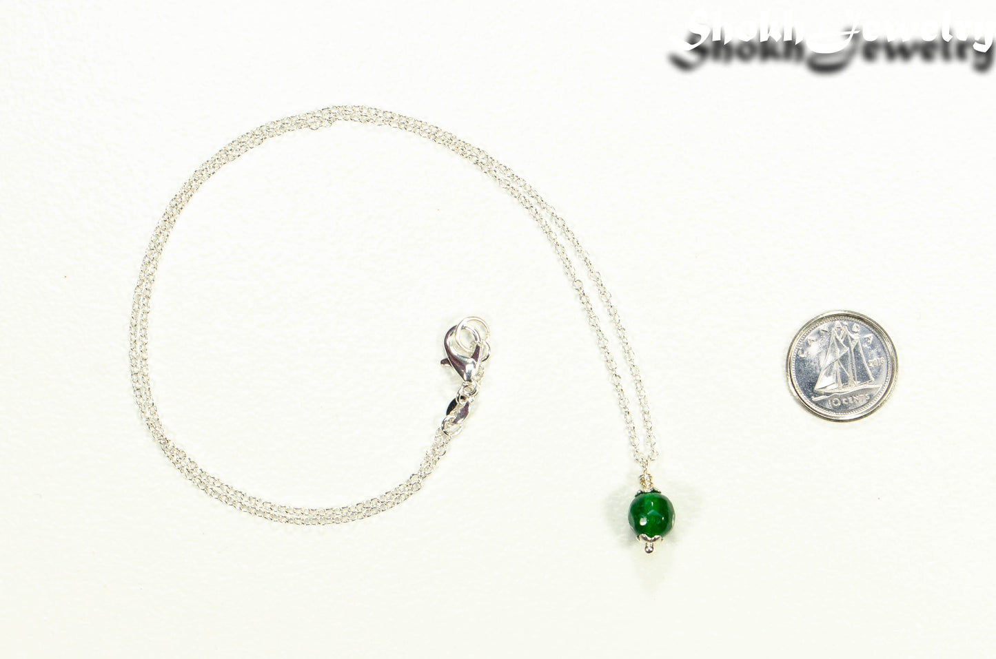 Dainty Emerald Choker Necklace beside a dime