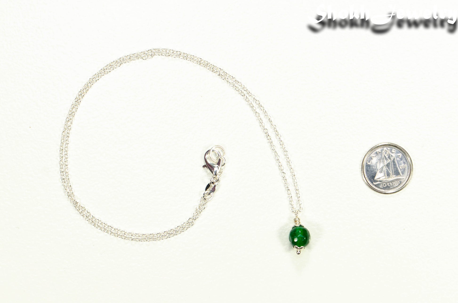 Dainty Emerald Choker Necklace beside a dime
